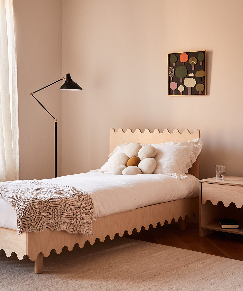 A minimalist bedroom features the Moss Twin Bed with a scalloped edge, complemented by white bedding, decorative pillows, and wall art.