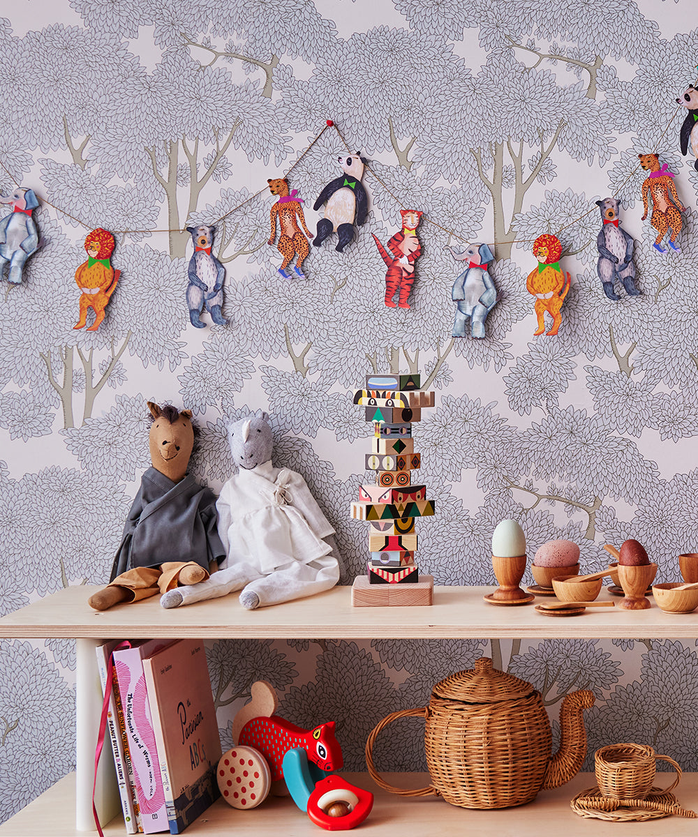 A childrens room features a Mini Library with stuffed animals, colorful garland, books, and wooden toys set against tree-patterned wallpaper.