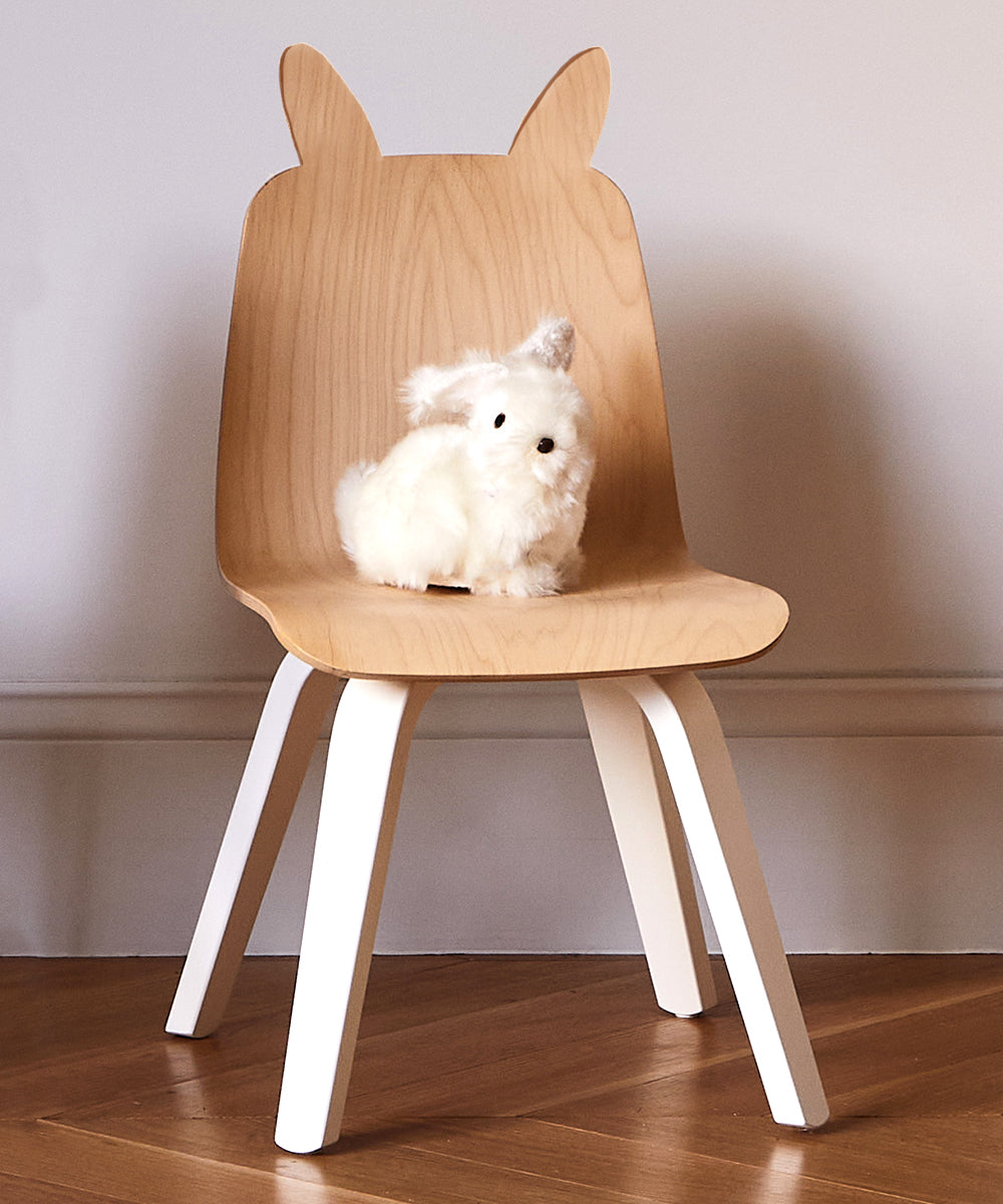 A Bunny Play Chair (Set of 2) with animal-like ears holding a small fluffy toy is placed in a room with wooden flooring.