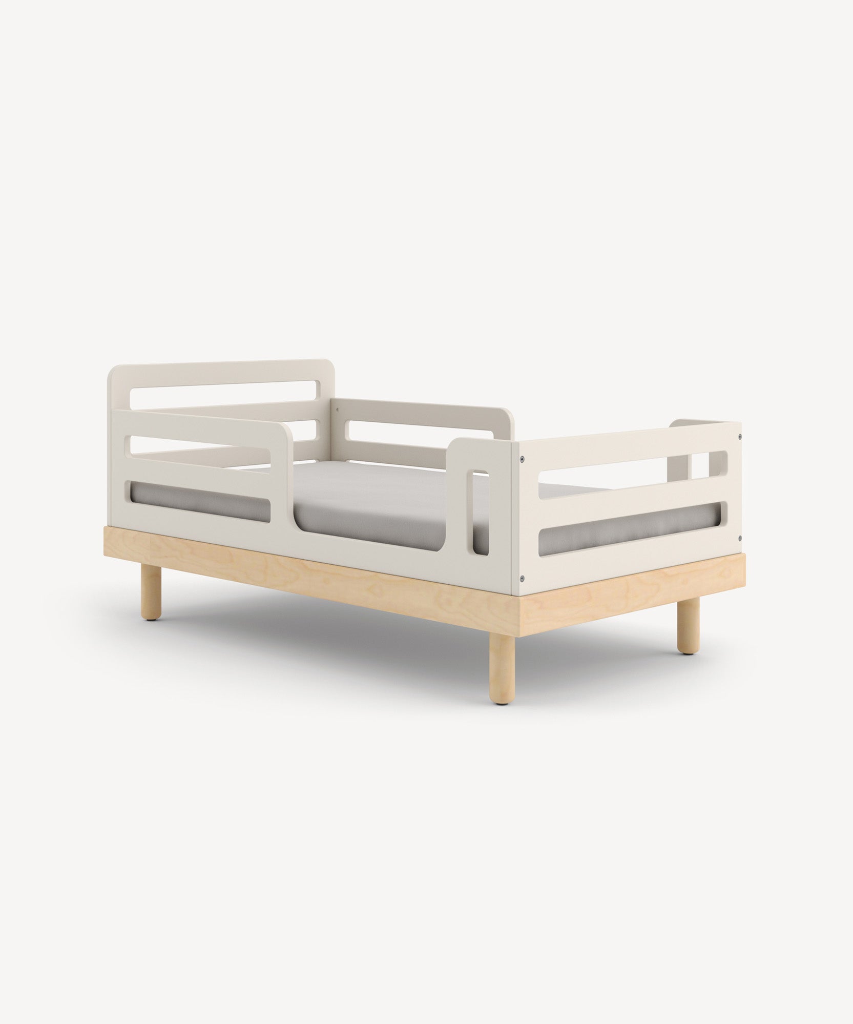 The Classic Toddler Bed features a minimalist design with light wooden legs, white guard rails, and a gray mattress.