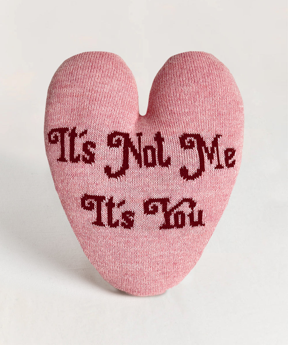 Heart Pillow - It's Not Me, It's You: A heart-shaped pillow with dark red text on a pink background.