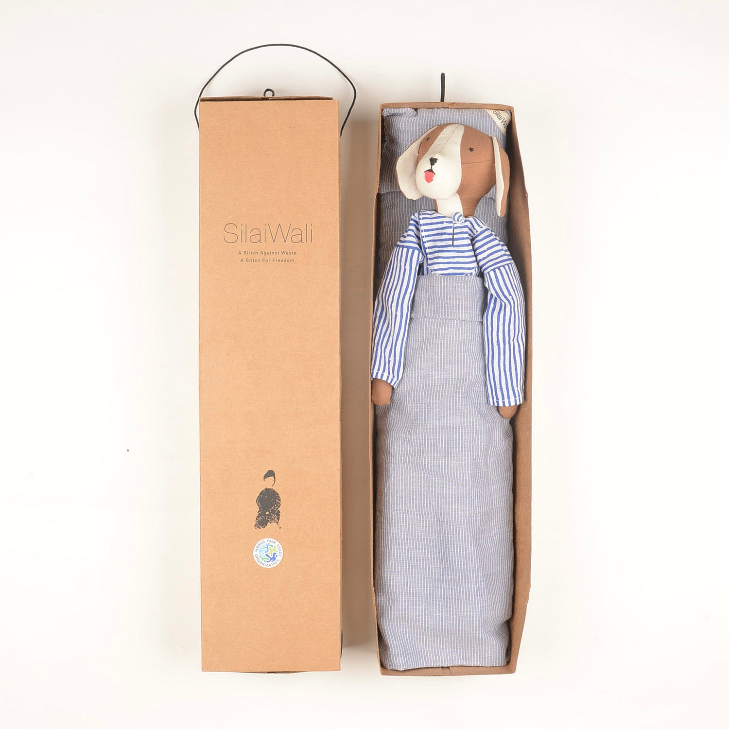 A Le Doggy stuffed animal toy in striped pajamas sits in an open cardboard box featuring SilaWali text and a small logo on the lid.