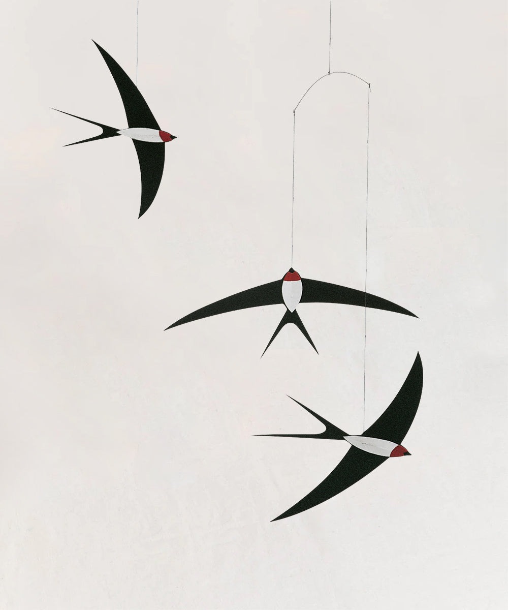 Against a plain background, three Le Mobile - Flying Swallows hang in minimalist black and white with red accents.