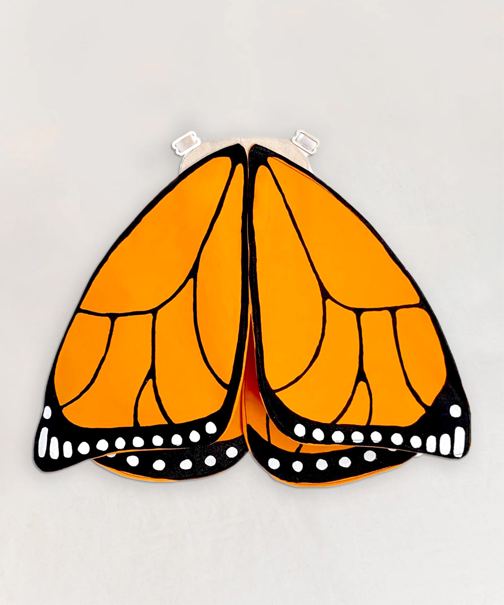 Le Monarch Butterfly Wings feature an orange and black design with white spots on a light gray background.