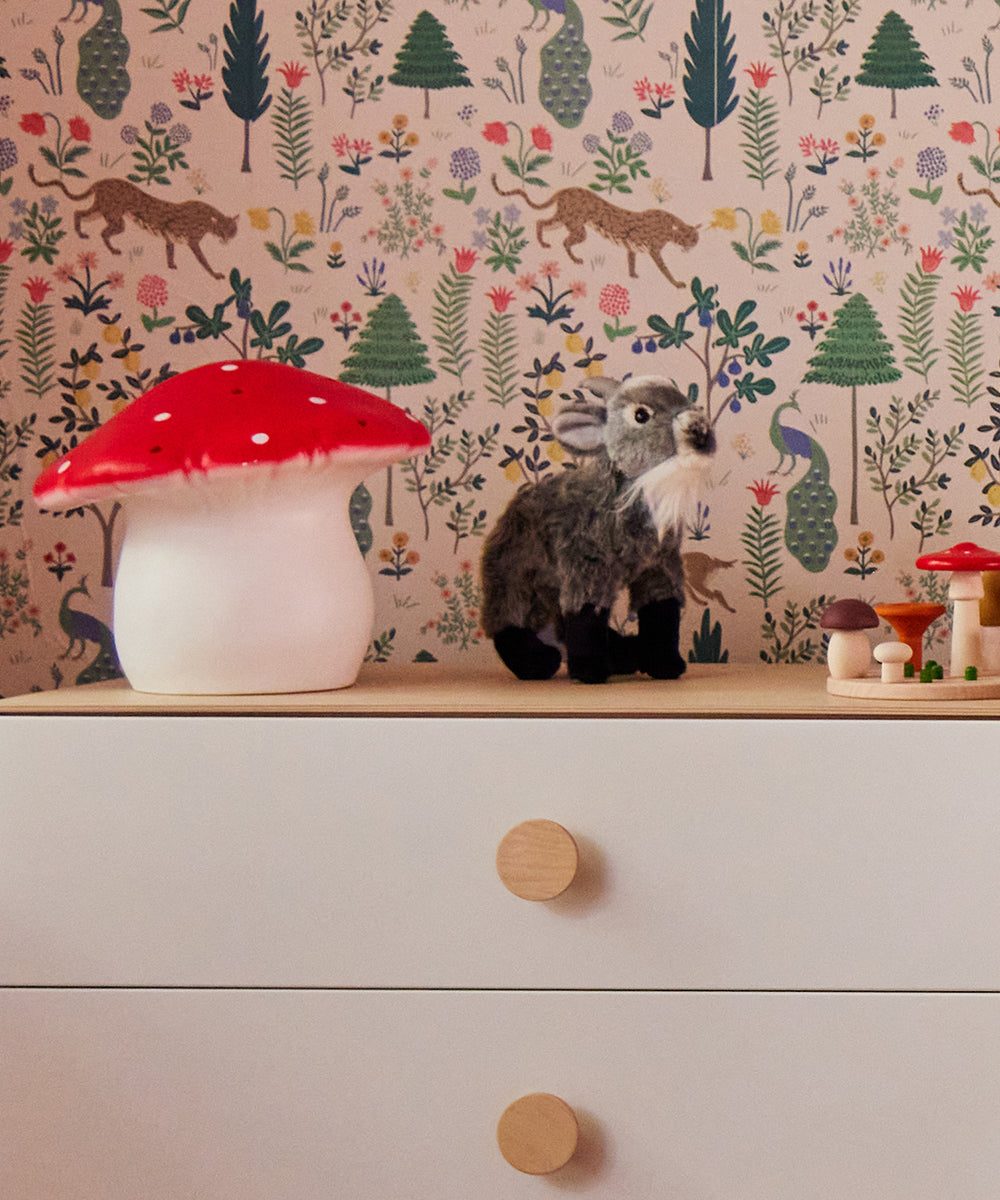 Dresser with a Le Big Mushroom Lamp, plush animal, and toy mushrooms against floral and animal print wallpaper.