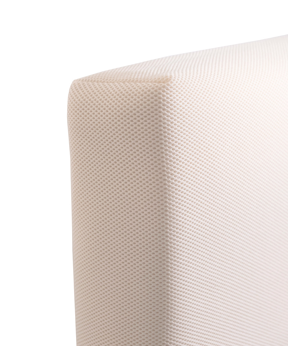 Close-up of a white textured corner, likely the Naturepedic Organic Breathable Baby Crib Mattress with a fine mesh-like surface.