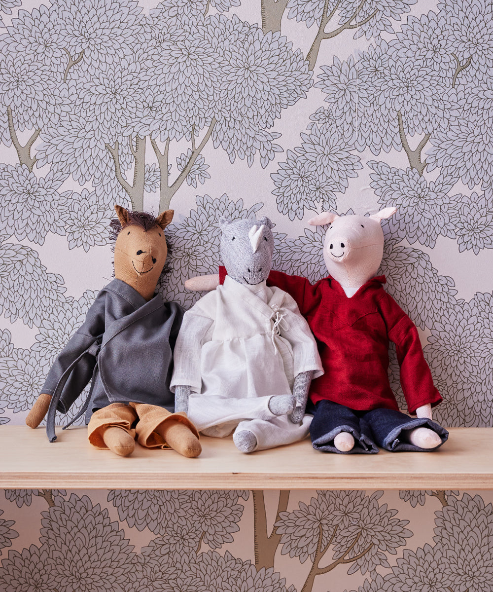 The fabric animal dolls, including Le Horsey, a rhino, and a pig, rest on a wooden shelf against tree-patterned wallpaper.