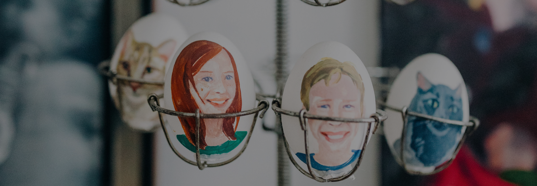 Eggs painted with human and animal faces are displayed in wire holders.