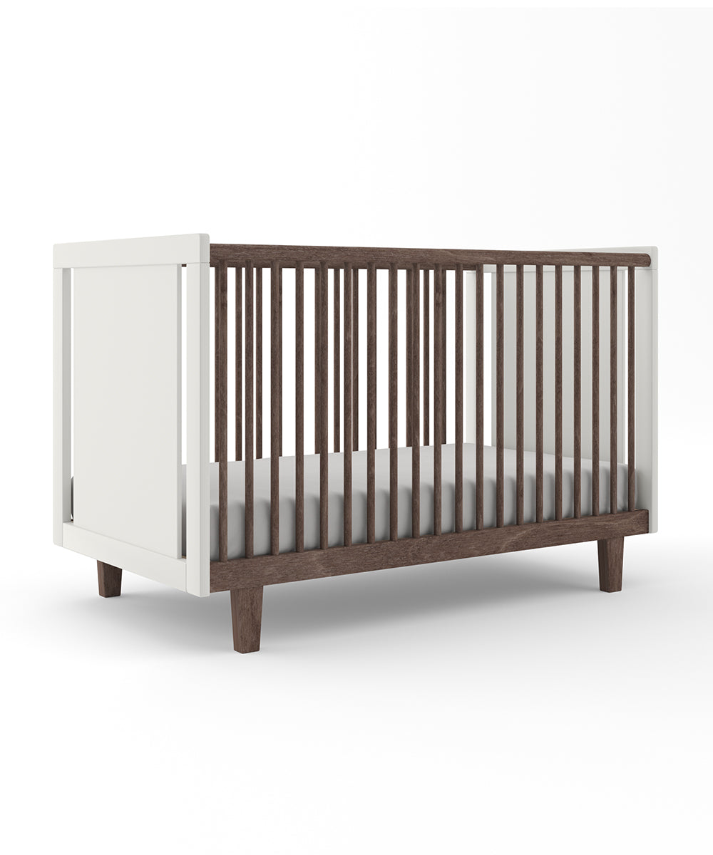 The Rhea Crib, a modern wooden baby crib with slatted sides and minimalist design, features white and brown accents on a white background.