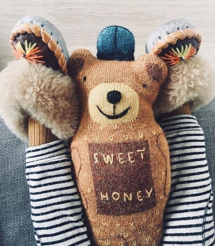 Honey Bear Pillow with "Sweet Honey," striped socks, fluffy slippers, and a pom-pom hat creates a cozy and playful scene.