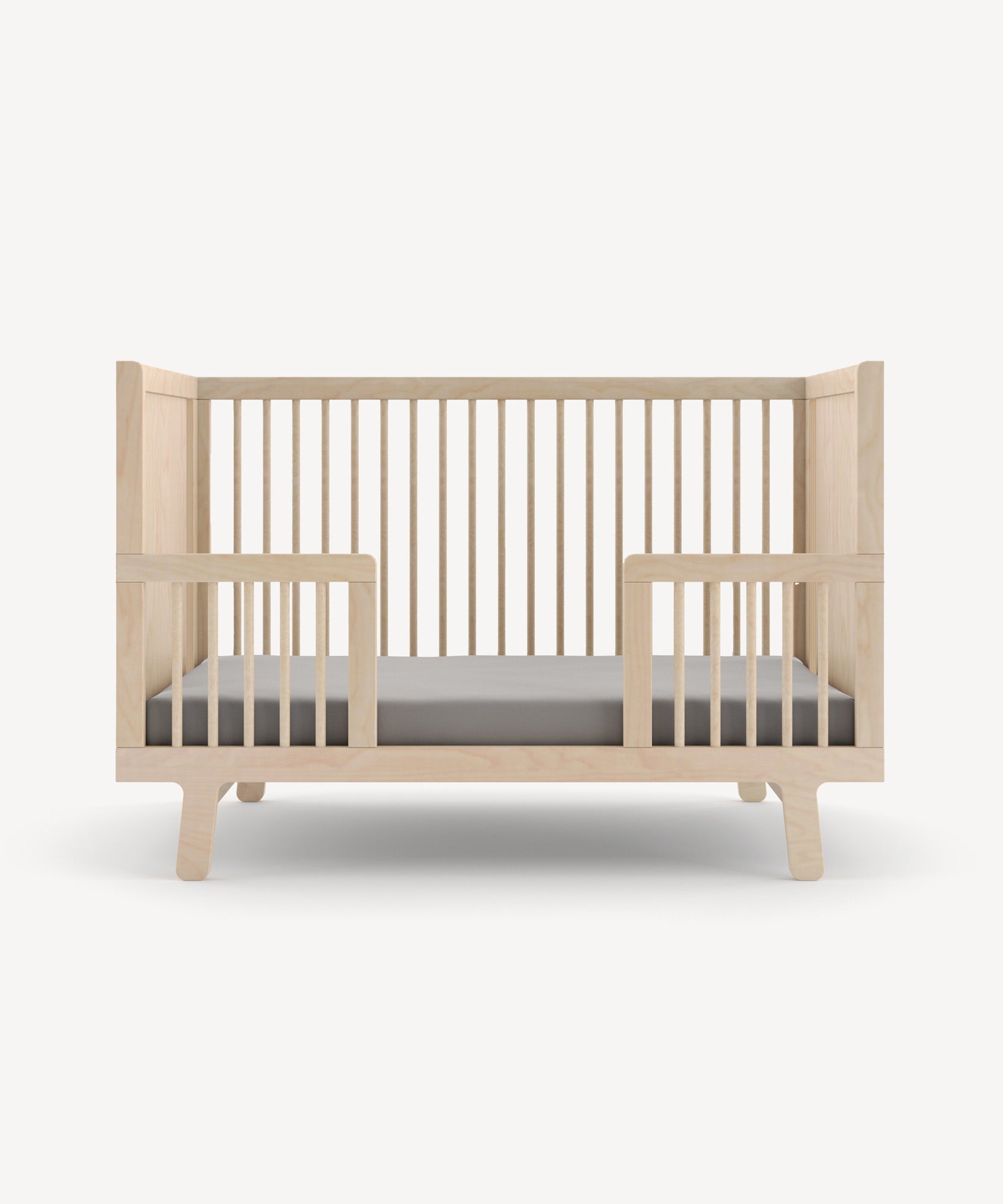 Sparrow Toddler Bed Conversion Kit featuring vertical slats and a low frame, paired with a gray mattress, on a simple background.