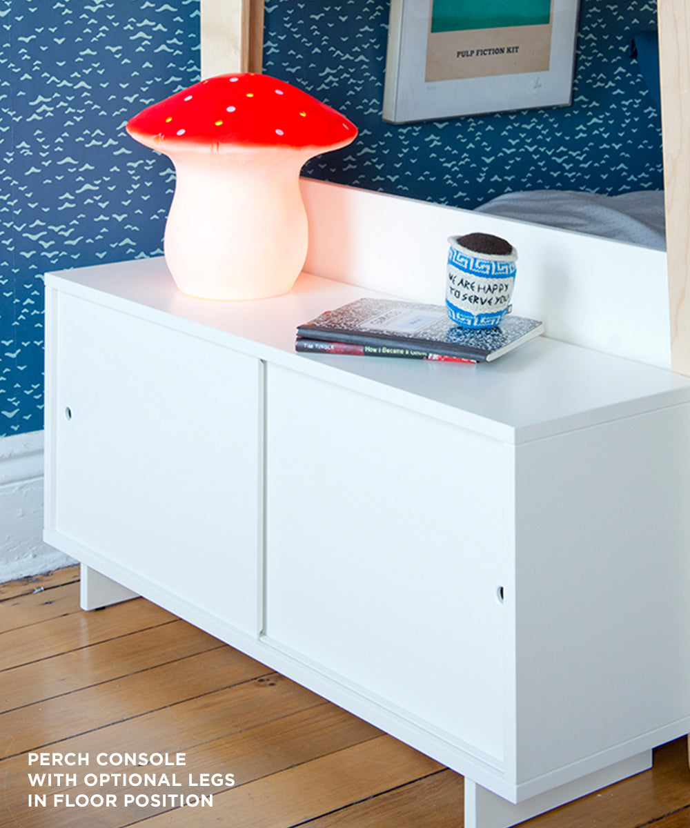 A Perch Console - Twin Size with a red mushroom lamp and a blue cup, set against a patterned wall.