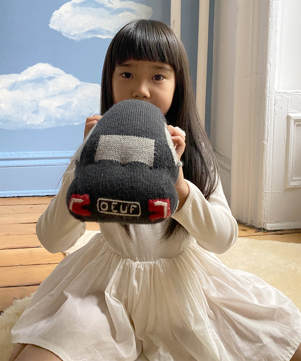 A long-haired child holds a My Ride Pillow in a room with cloud-painted walls.