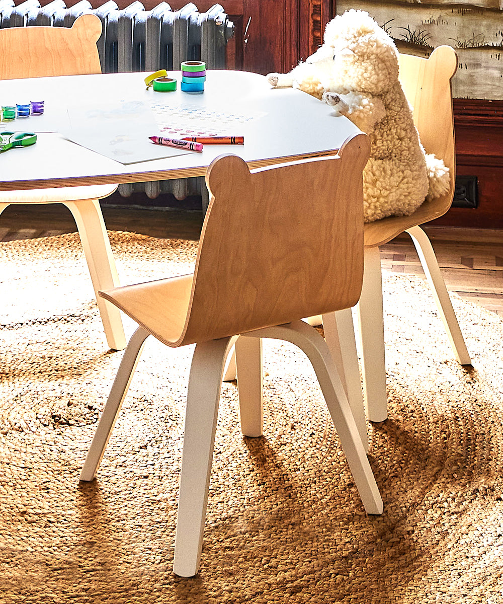 A childrens playroom featuring a Bear Play Chair (Set of 2) with art supplies on the table, all set on a woven rug.