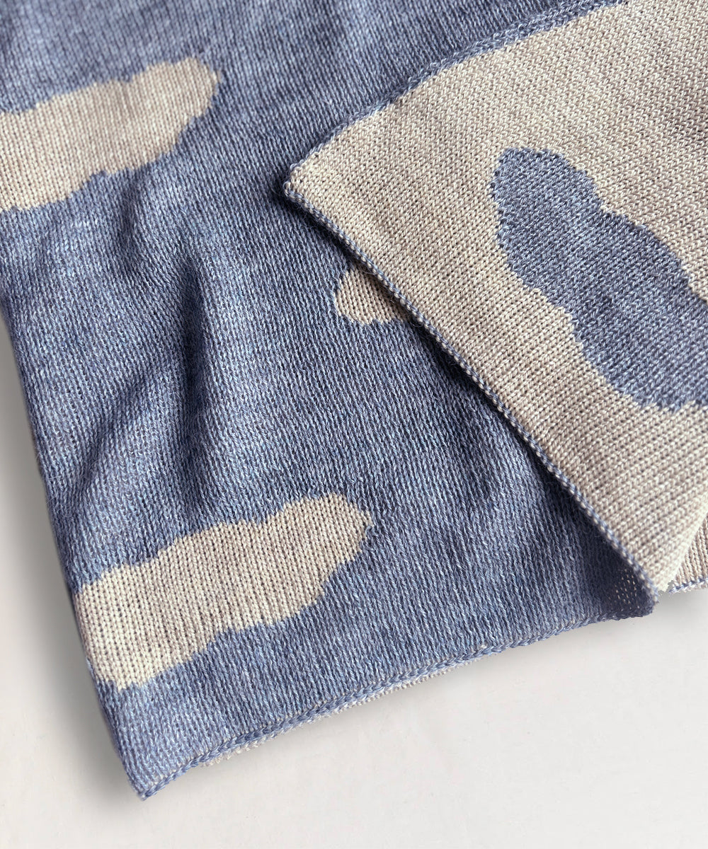 Close-up of a Cloud Blanket, featuring a blue and beige cloud pattern, folded neatly on a surface.