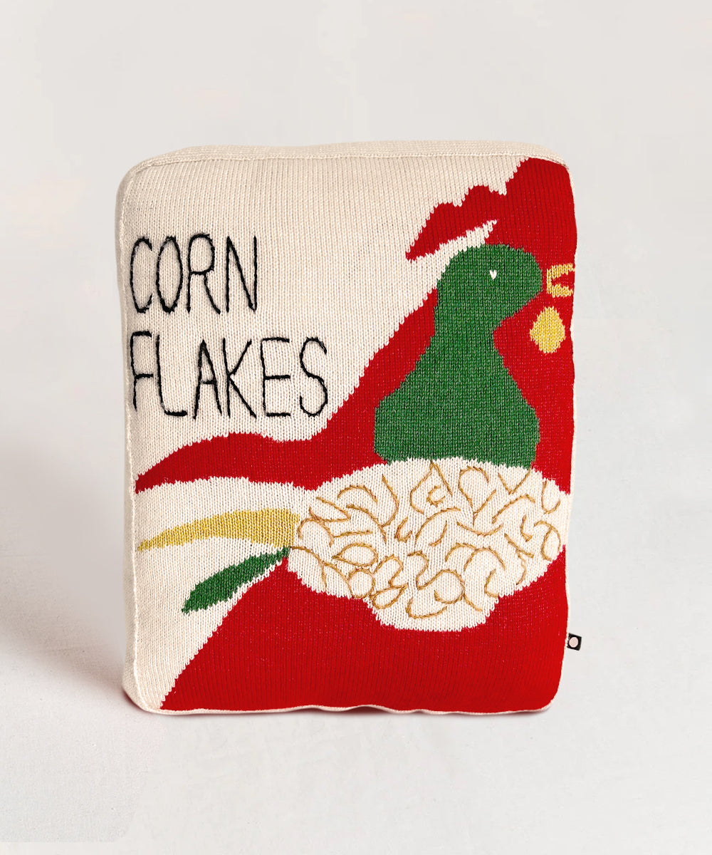 Corn Flakes Pillow featuring a vibrant rooster graphic and text on a red and beige background.