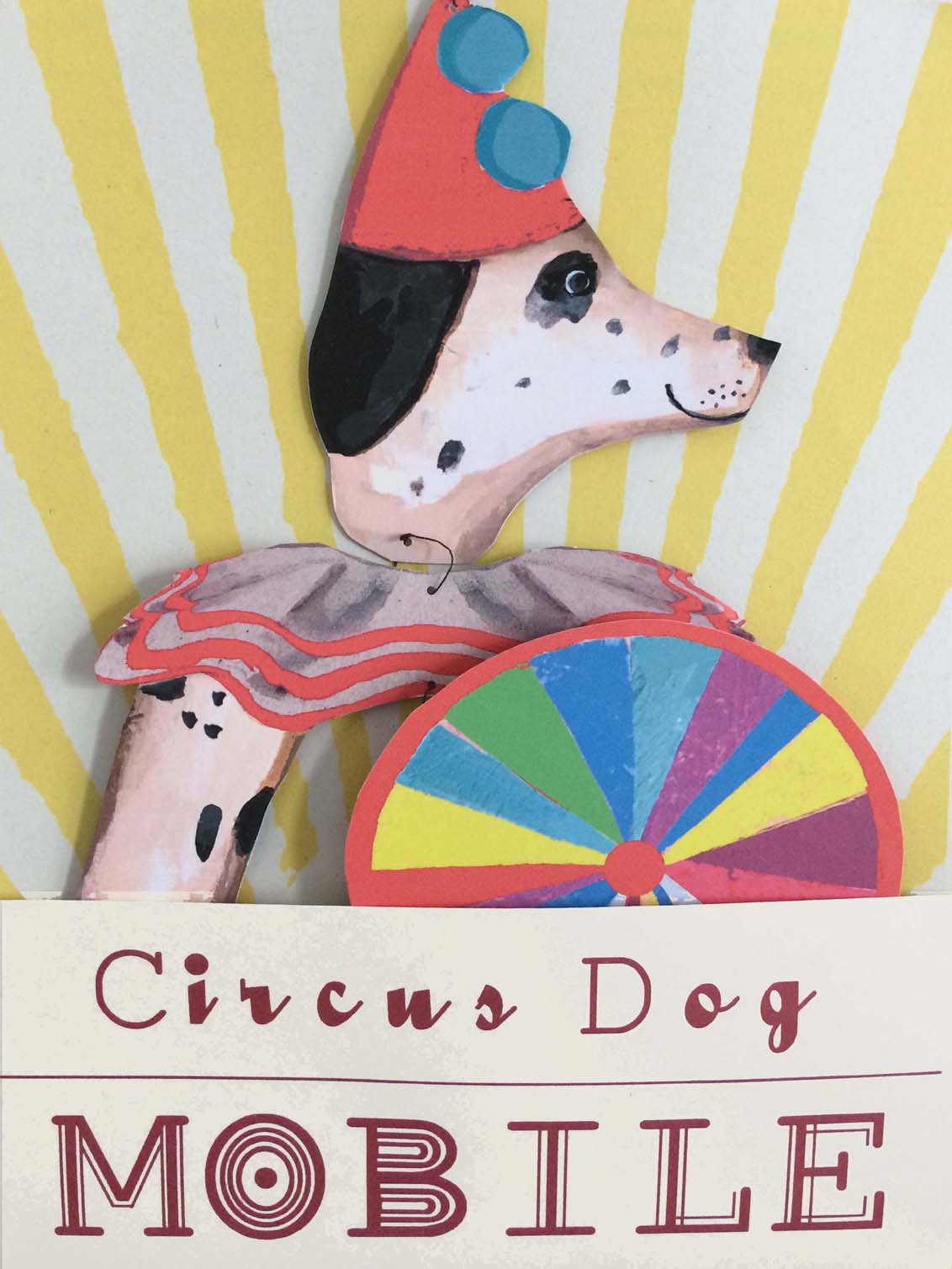 An illustrated circus dog in a red hat and tutu holds a colorful wheel on a sunburst background. Text reads Le Mobile - Circus Dog.