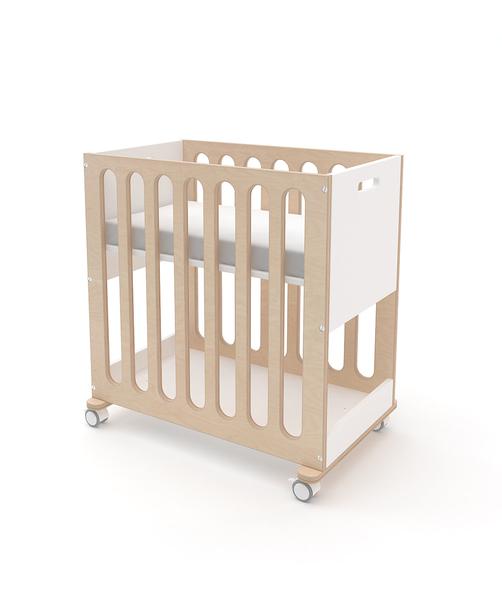 The Fawn 2-in-1 Crib System features a wooden design on wheels with one side in white, shown from an angled perspective.