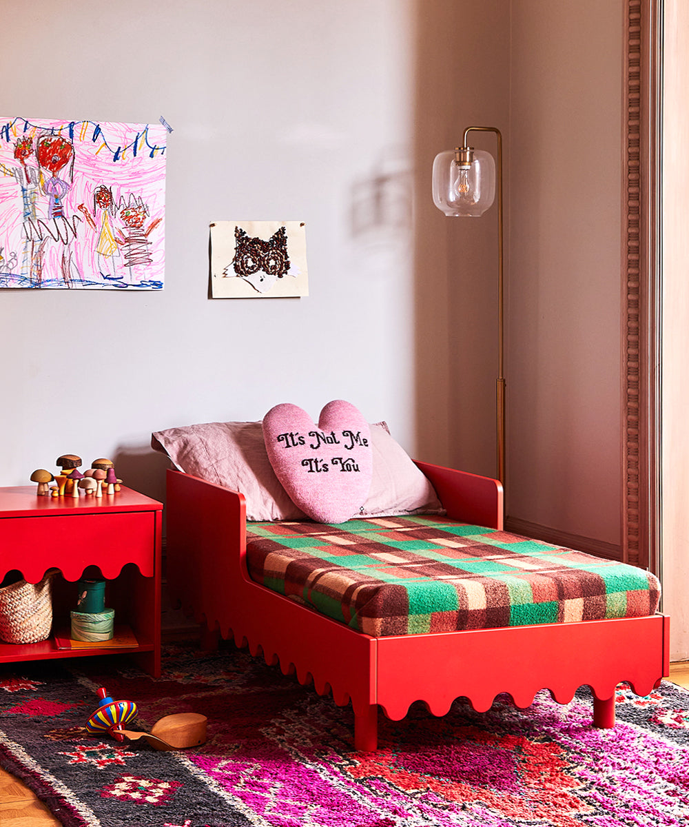 Childrens bedroom featuring a red bed, Moss Nightstand, heart-shaped pillow, and vibrant decor on the walls and rug.