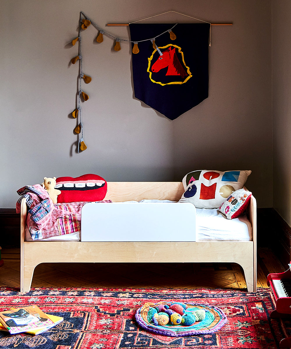 Cozy childs room featuring the Perch Toddler Bed, vibrant pillows, a decorative banner, and string lights.