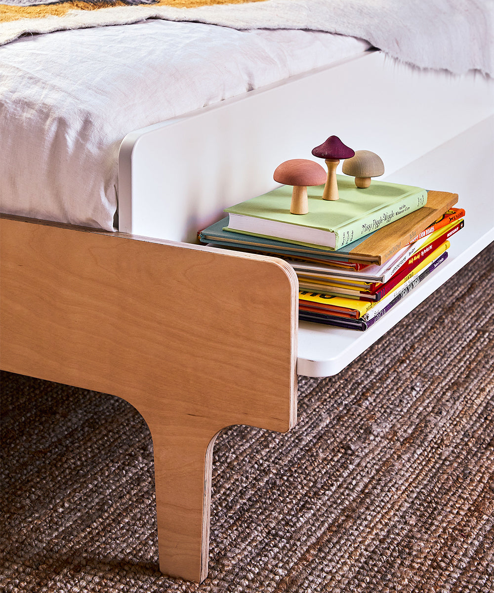 The River Full Bed features a shelf perfect for books and decorative mushrooms, complemented by a woven rug underneath.