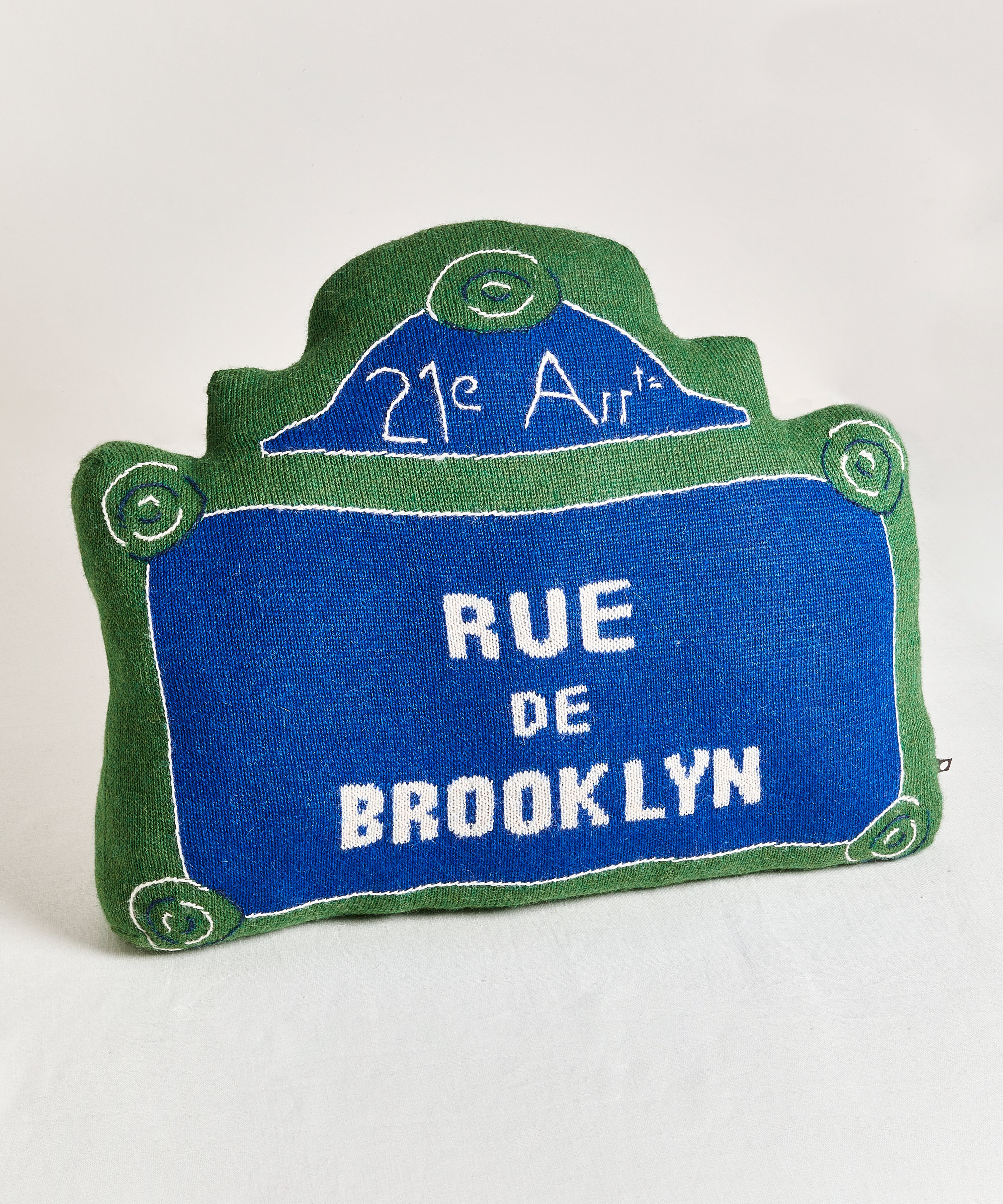 A Rue de Brooklyn Pillow mimics a French street sign with green and blue hues.