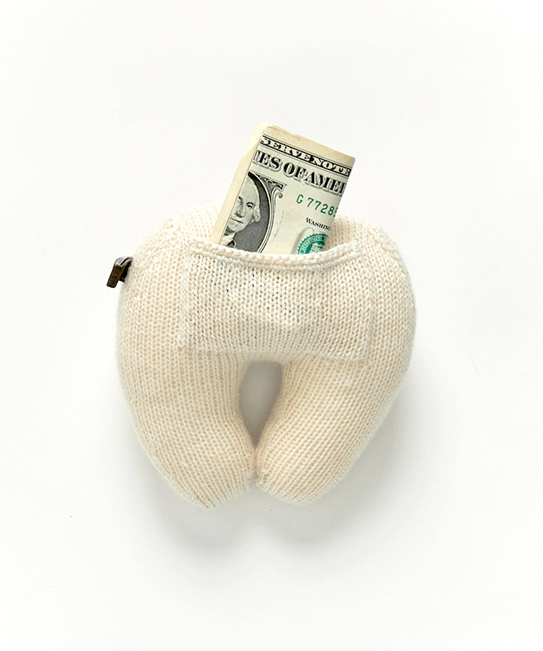 White knit Tooth Fairy Pillow with a dollar bill sticking out.