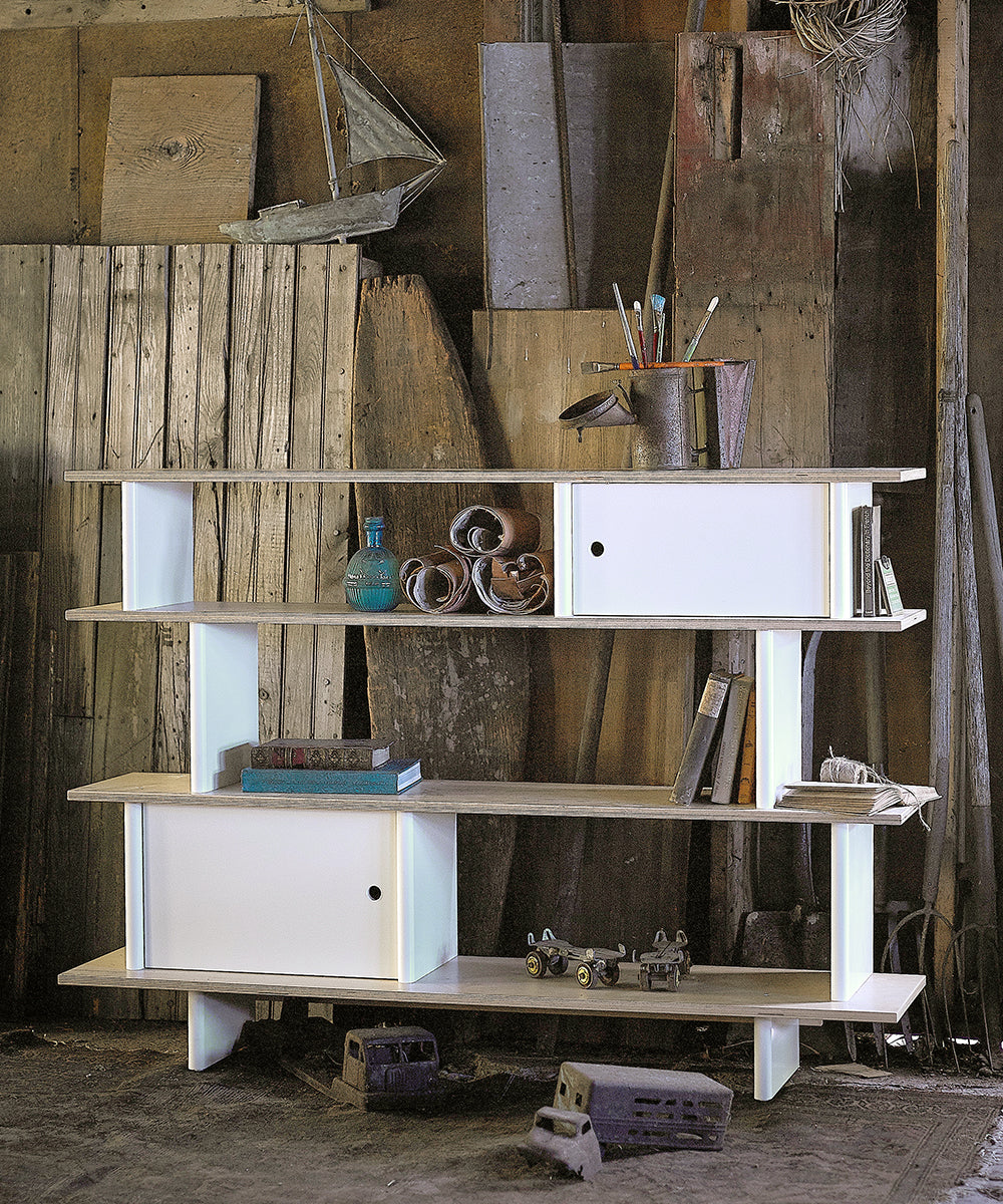 A Mini Library featuring white cabinets, art supplies, a toy car, bricks, and various decorative items in a rustic setting.