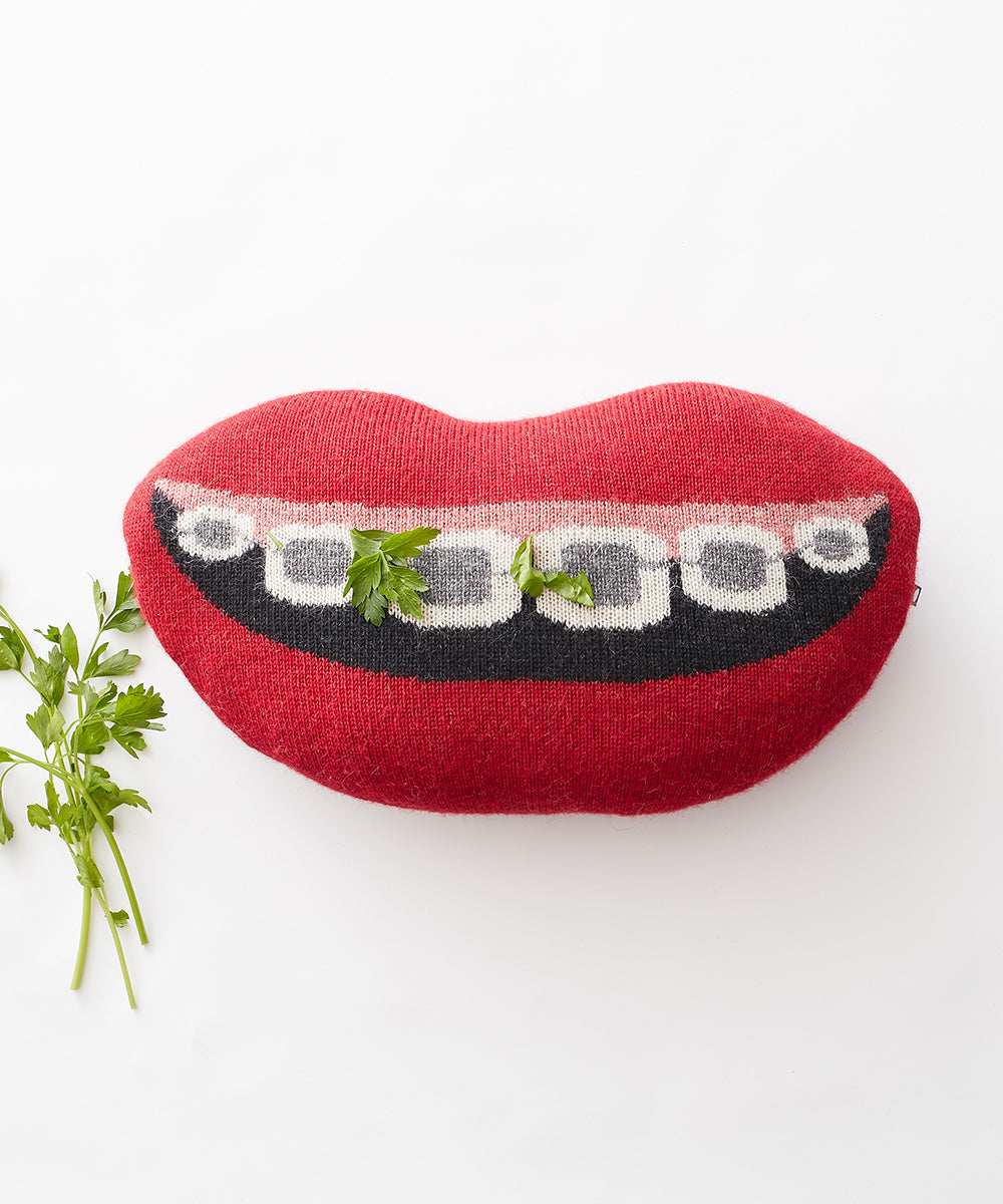 Mouth Pillow - Braces: A red, lip-shaped pillow featuring a braces design with green parsley leaves, set on a white surface.