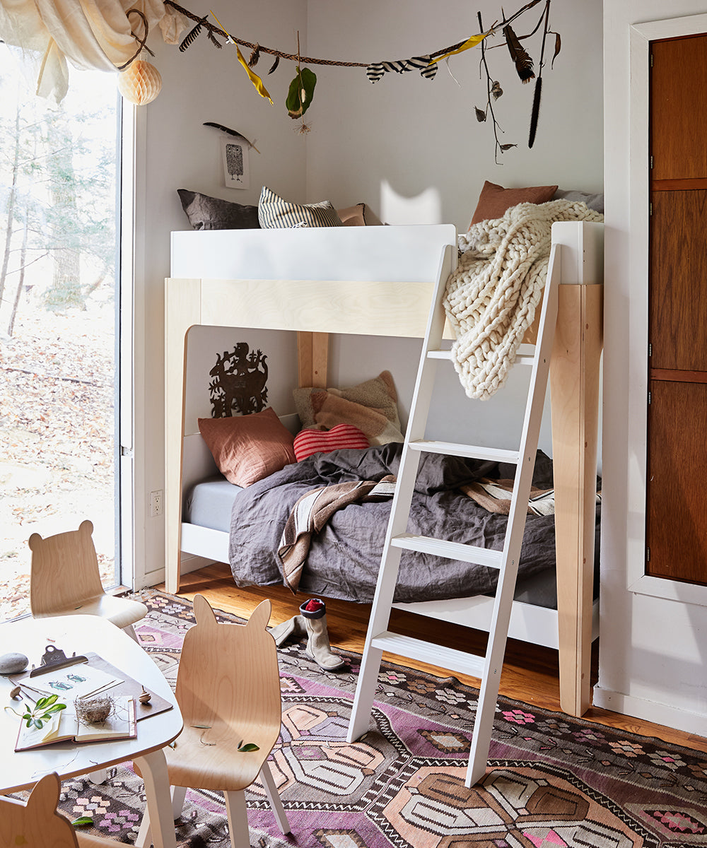 Cozy kids room featuring the Perch Twin Bunk Bed, wooden chairs, a colorful rug, and nature-themed decor.