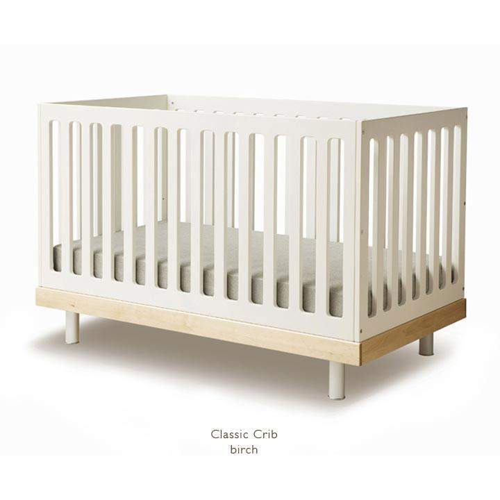 The Classic Crib Sides is a wooden crib in white and birch with vertical slats, complete with a mattress.