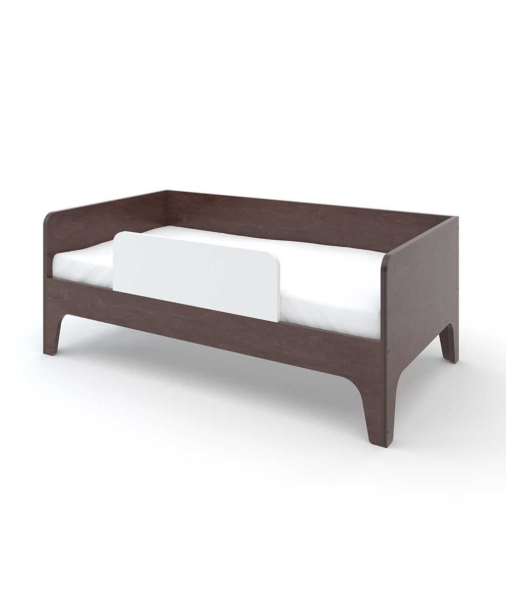 Perch Toddler Bed: A dark wooden toddler bed featuring a white safety rail, isolated on a white background.