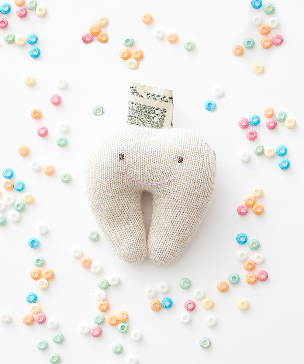 Tooth Fairy Pillow with a dollar bill, displayed on a white background and surrounded by colorful cereal.